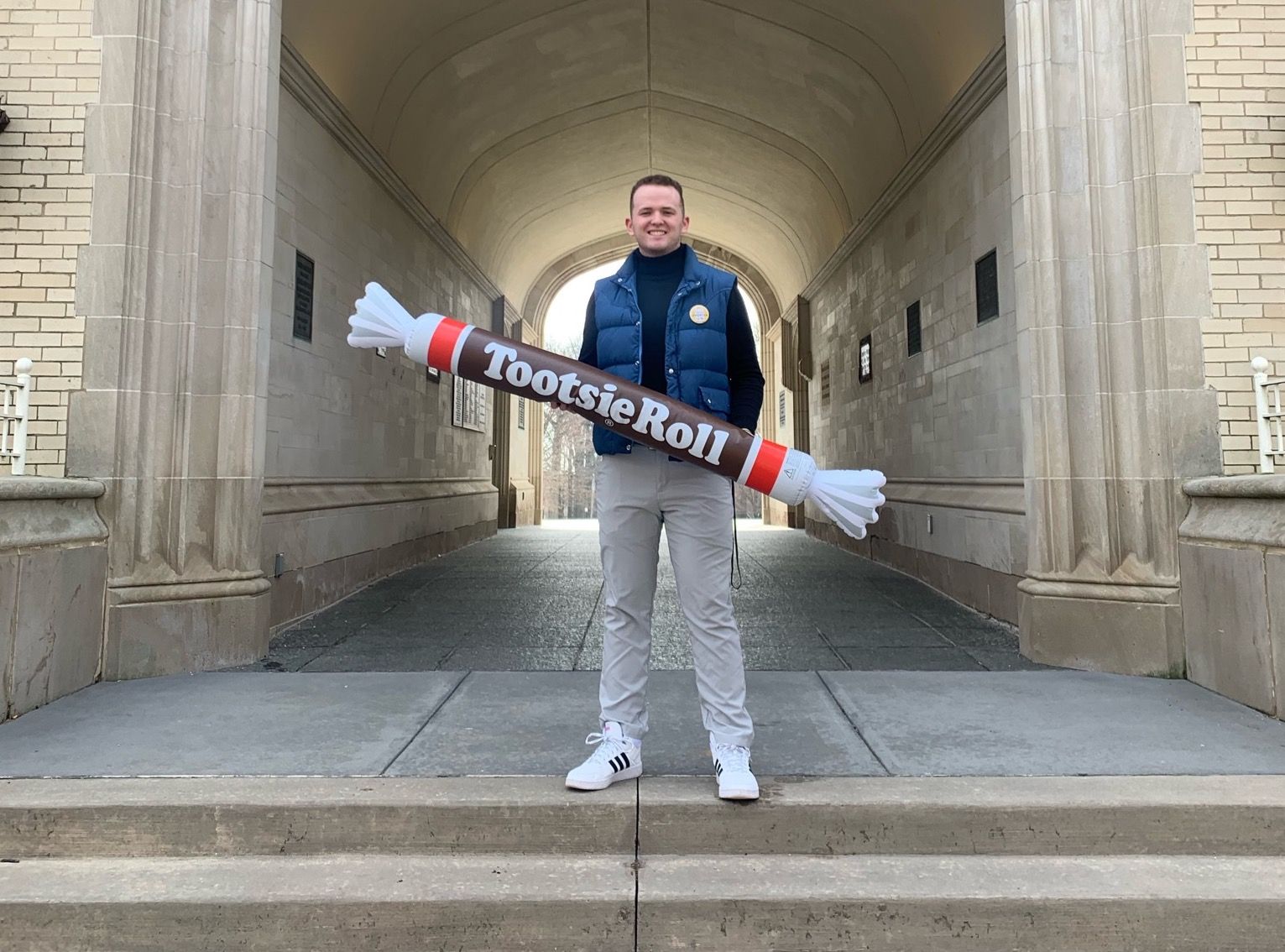Wyatt Shafter standing in front of an archway holding an inflatable Tootsie Roll prop