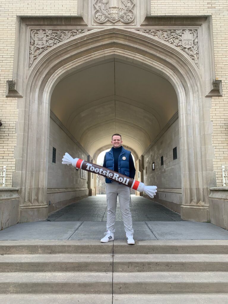Wyatt Shafer poses on campus at Wooster College with a large inflatable Tootsie Roll