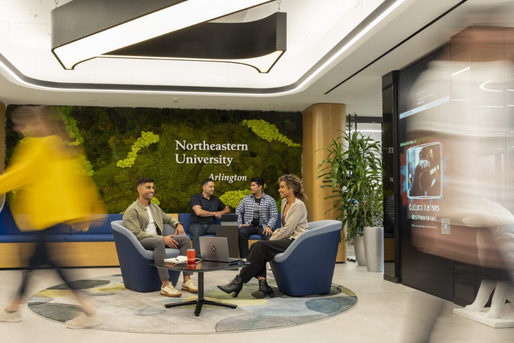 A photo of students gathering in the common area of the campus while others walk by