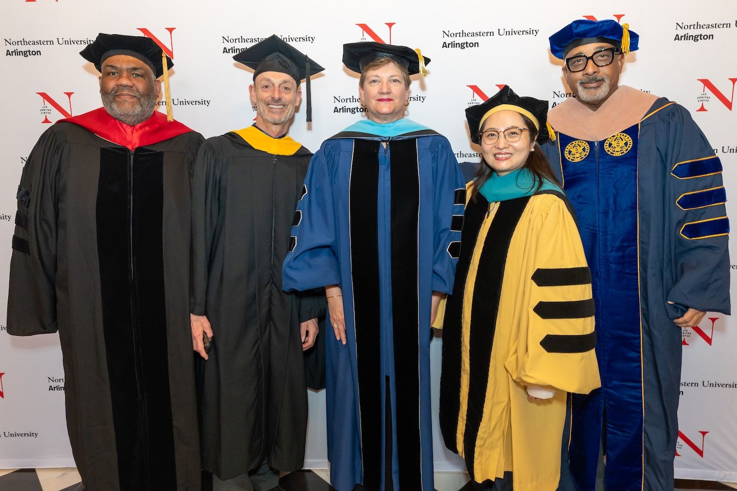 At the Arlington campus commencement, faculty pose together in their regalia before the ceremony